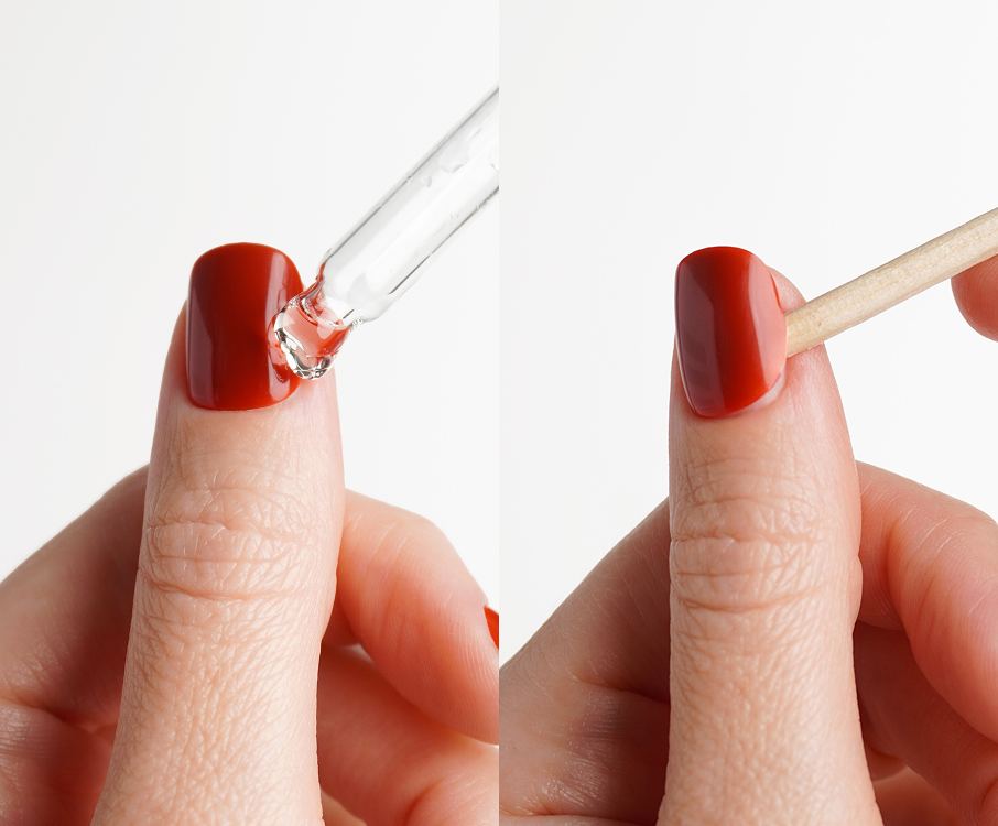 Gently lifting a press on nail with a wooden stick after applying cuticle oil